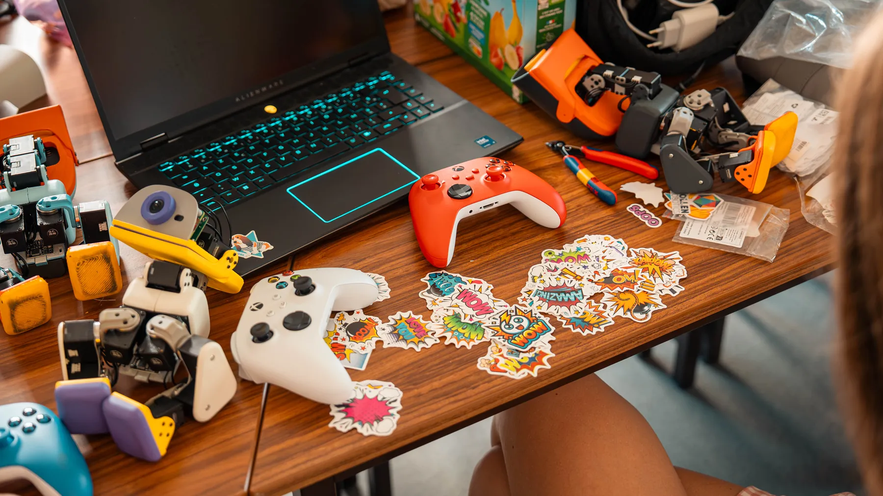 Overhead view of a desk with MACRODUCKs, a game controller and a sticker sheet